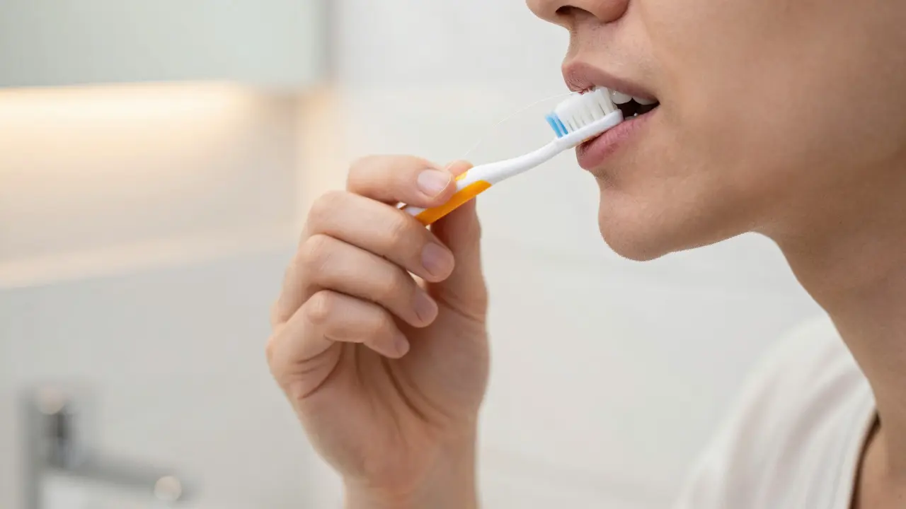 Ruce drží měkký kartáček a dentální nit pro péči o zuby